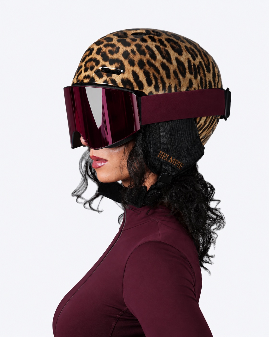 Leopard ski helmet with burgundy goggles and embroidered HELMPIE ear pad, side profile