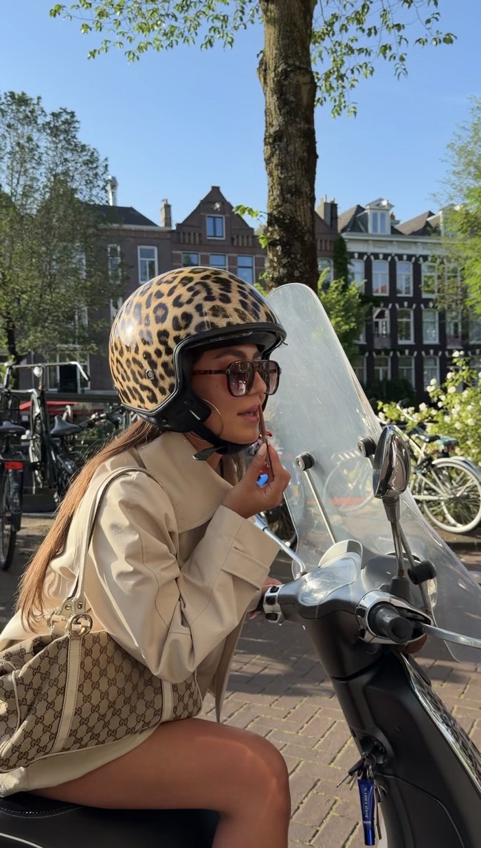 Wearing the Leopard Scooter Helmpie on the scooter beside an Amsterdam canal